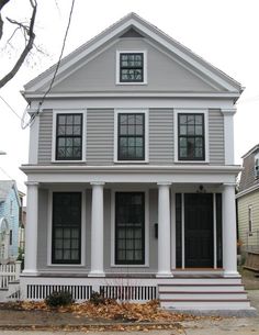 a gray two story house with white trim and black shutters on the front porch