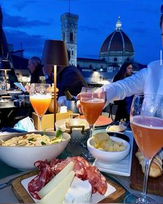 a man sitting at a table with wine, cheese and meats in front of him