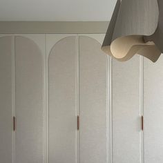 a room with some white cabinets and a light hanging from it's ceiling over the bed