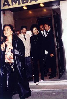 a group of people standing in front of an amba store entrance with the door open