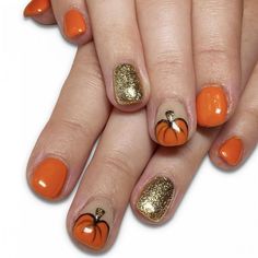 an orange and gold manicure with pumpkins on it