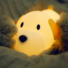 a stuffed animal laying on top of a bed next to a light up teddy bear