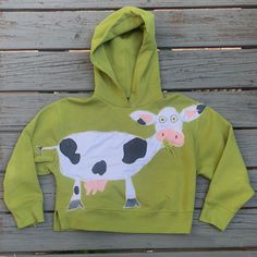 a child's green hoodie with a cow painted on the front and side