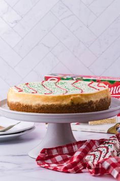 a cheesecake sitting on top of a white cake plate next to a box of christmas crackers