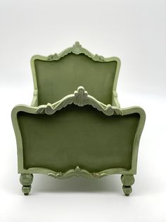 an old fashioned green bed frame sitting on top of a white floor