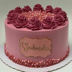 a pink cake with purple frosting and roses on the top is decorated with nameplates