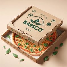 two pizzas with basil on top are sitting in a box next to some leaves