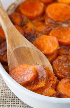 a wooden spoon in a bowl filled with cooked carrots