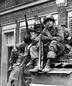 black and white photograph of soldiers sitting on top of an armored vehicle