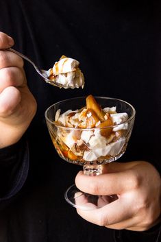 a person holding a spoon full of dessert with whipped cream and caramel on top