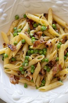 pasta with peas and bacon in a white bowl