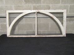 an old white arched window sitting on top of a black table