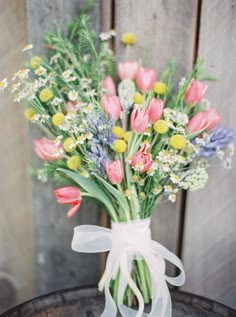 a bunch of flowers that are sitting in a vase on a table with ribbon around it