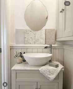 a white sink sitting on top of a bathroom counter next to a wall mounted mirror