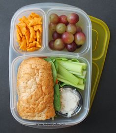 a plastic container with grapes, celery, cheese and crackers in it