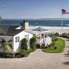 the house is surrounded by greenery and palm trees, with an ocean view in the background