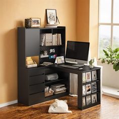 a computer desk with a laptop on top of it next to a book shelf and window