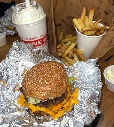 a hamburger and fries are sitting on tin foil