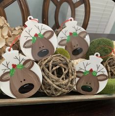 christmas ornaments with reindeer faces and antlers are sitting on a table in front of some wood logs