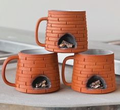 three brown mugs sitting on top of a table next to each other and one has a hole in the middle