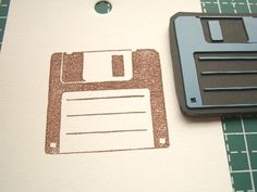 a rubber stamp with a floppy disk on it and a piece of paper next to it