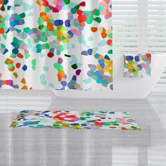 a colorful shower curtain and rug in a bathroom