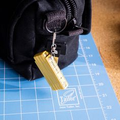 a black bag with a yellow tag hanging from it's side on a ruler