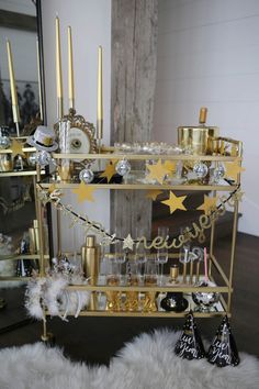 a gold bar cart filled with champagne glasses and confetti on a white fur rug