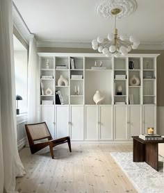 a living room filled with lots of white furniture and shelves on top of each other