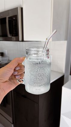 a person holding a mason jar with a straw in it and the lid is clear