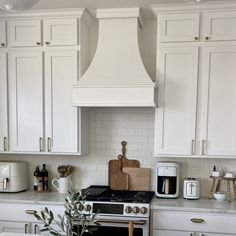 a kitchen with white cabinets and an oven in the center, surrounded by wooden utensils