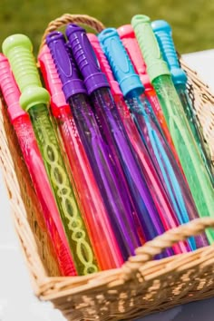 a basket filled with lots of different colored pens on top of a white tablecloth