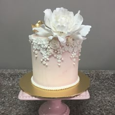 a pink and gold cake with flowers on top