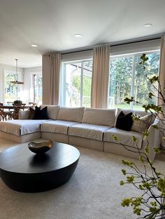 a living room filled with lots of furniture and large windows in the back ground area