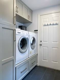 a washer and dryer in a room with white cabinets on either side of the door