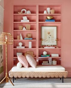 a living room with pink walls and bookshelves