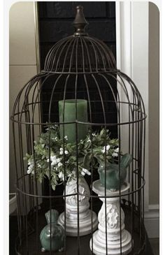 a birdcage filled with flowers and candles on top of a table