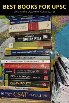 a stack of books sitting on top of a wooden table next to a world map