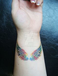 a woman's arm with an angel tattoo on the wrist and colorful wings painted on it