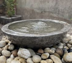 a stone bowl is sitting on top of some rocks and water in the middle of it