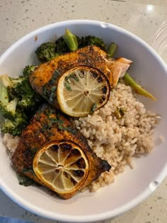 a white bowl filled with fish, rice and broccoli on top of a table