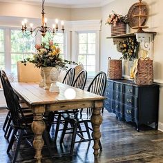 a dining room table with chairs and vases on top of it in front of windows