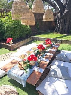 a long table with red flowers on it in the middle of some grass and trees