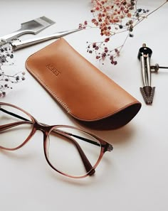 a pair of glasses sitting on top of a table next to a pen and eyeglass case