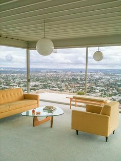 a living room filled with furniture and a large window overlooking the cityscape in the distance