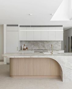 a large kitchen with marble counter tops and white cabinetry, along with an island in the middle