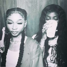 two young women drinking from cups while standing next to each other