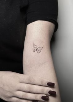 a woman's arm with a small butterfly tattoo on the left side of her arm