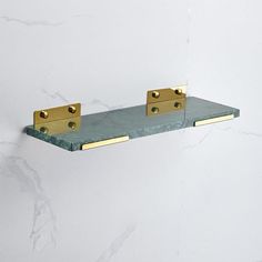 two brass brackets on a green marble shelf