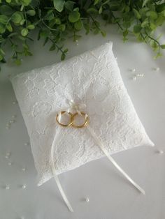 two gold wedding rings on top of a white ring pillow